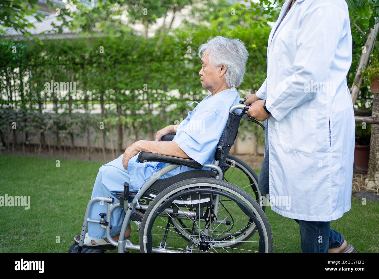 Doctor help and care Asian senior or elderly old lady woman patient sitting on wheelchair at park in nursing hospital ward, healthy strong medical con Stock Photo