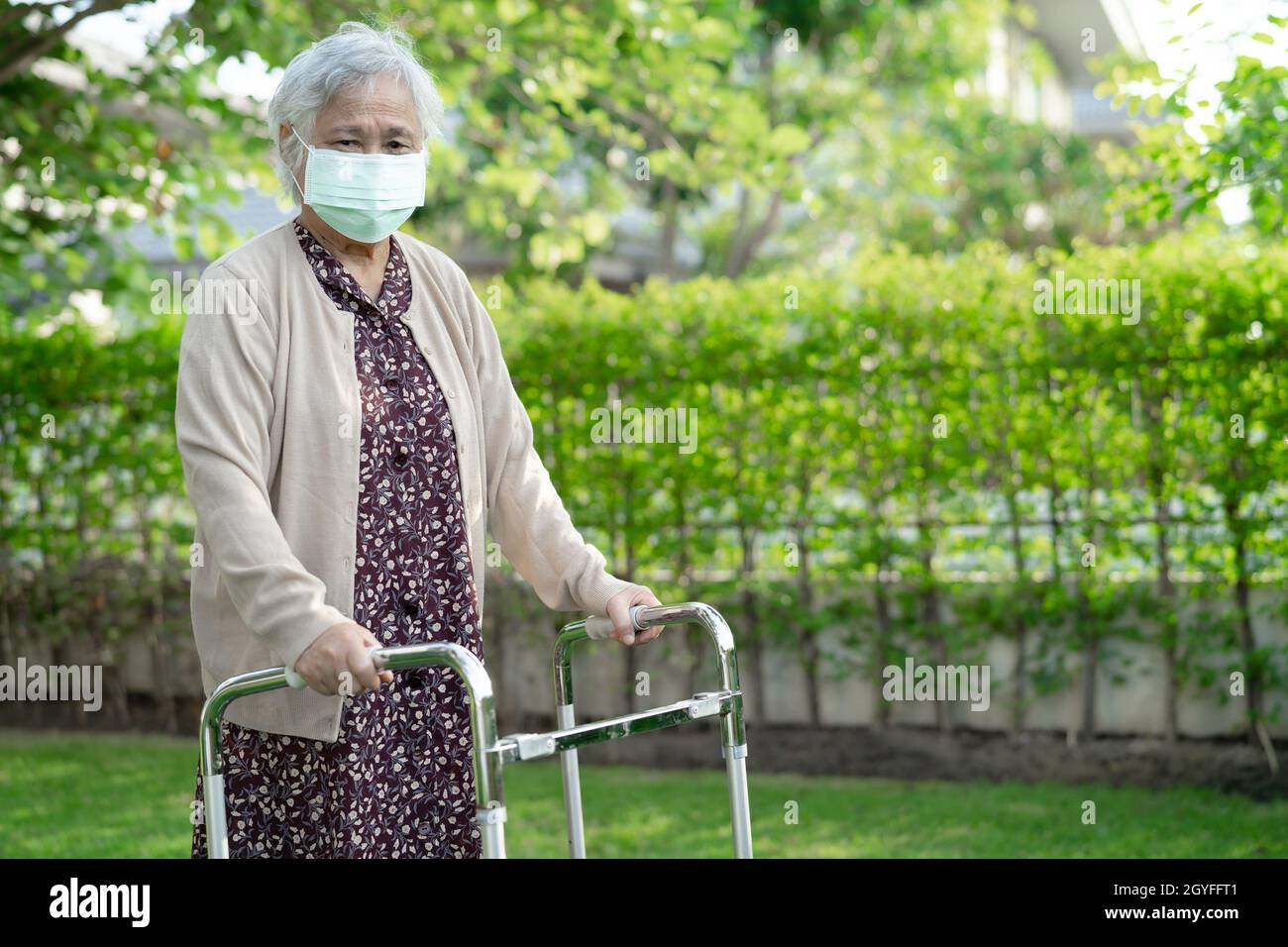 Asian senior or elderly old lady woman walk with walker and wearing a ...