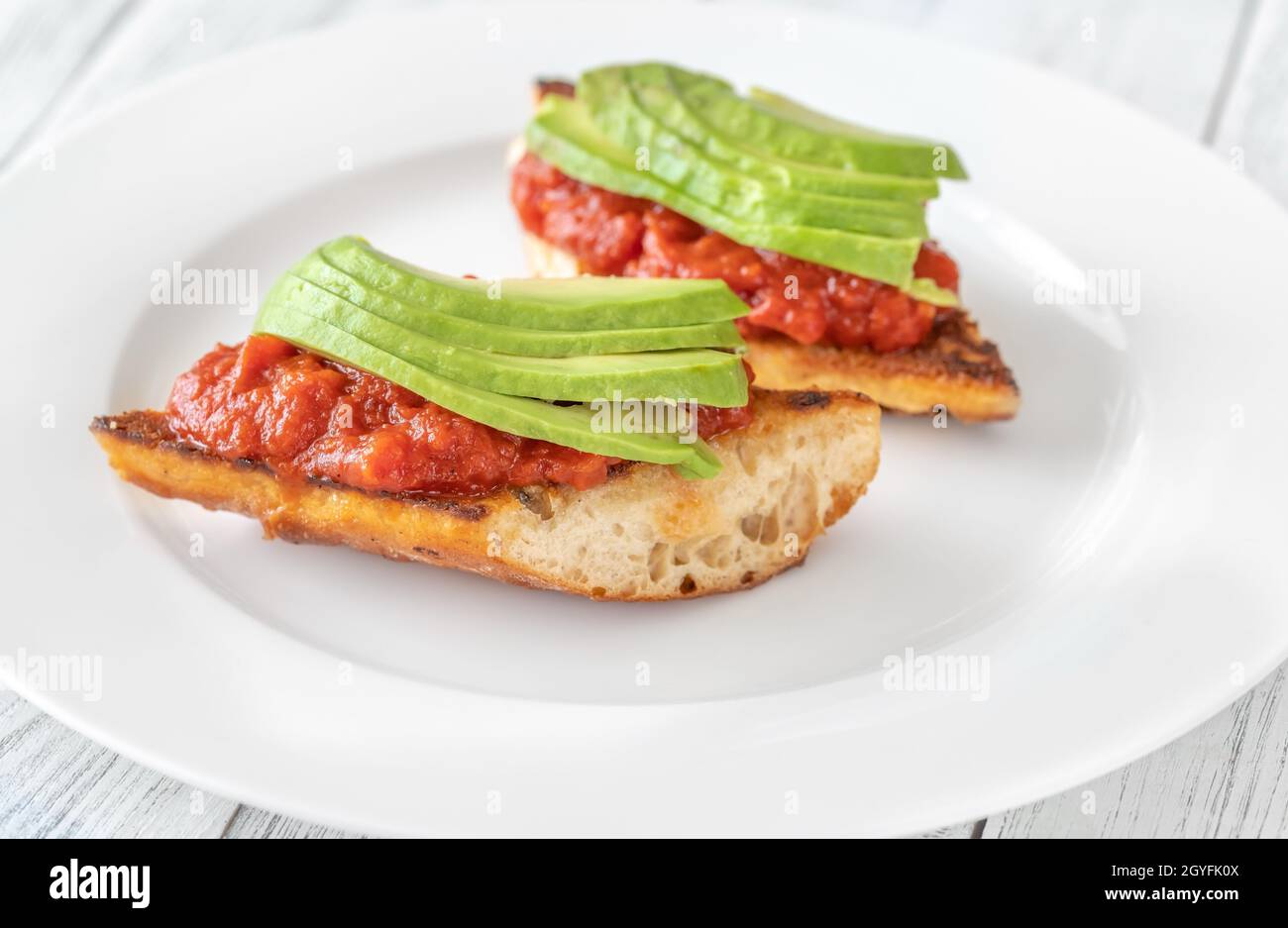Bruschettas with tomato spread and slices of avocado Stock Photo