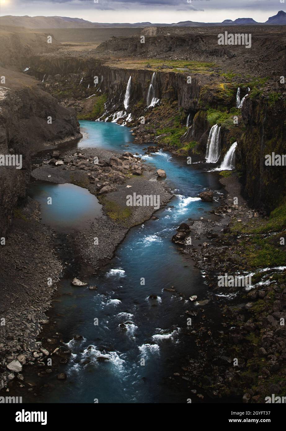 Vertical shot of small waterfalls and a river flowing amid the rocks ...