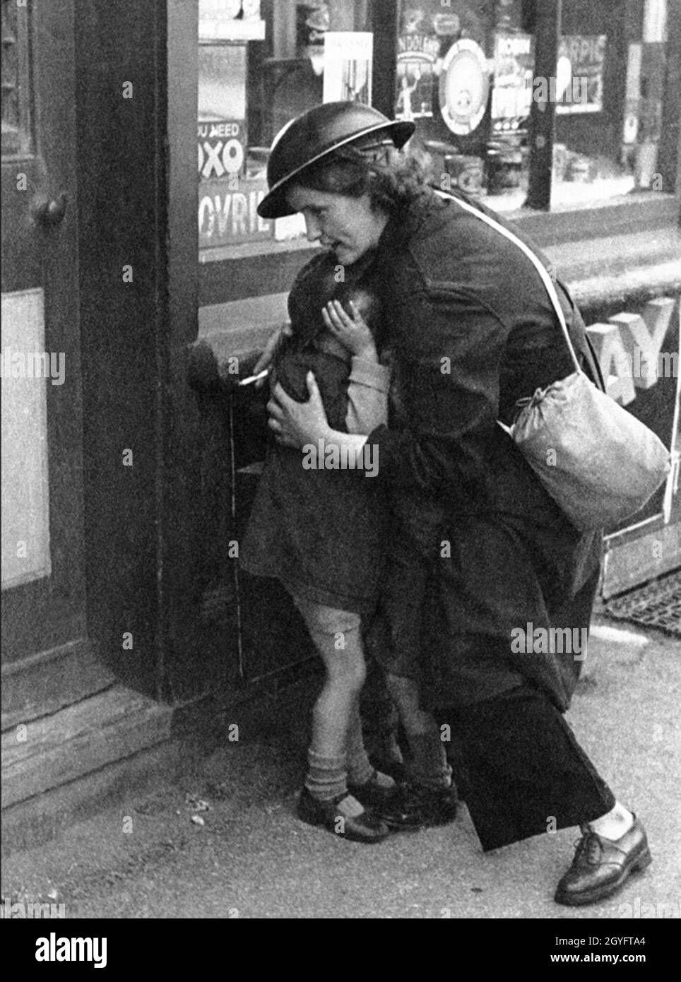 A young woman (Mary Couchman), working as an Air Raid Warden shielding young children as bombs fall during the Blitz, London 1940. Stock Photo