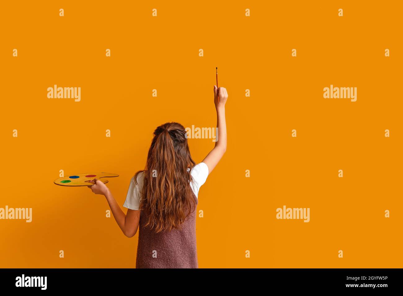 Cute little girl painting on color wall Stock Photo Alamy