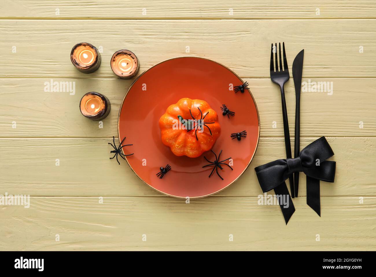 Halloween table setting with pumpkin and candles on yellow wooden ...