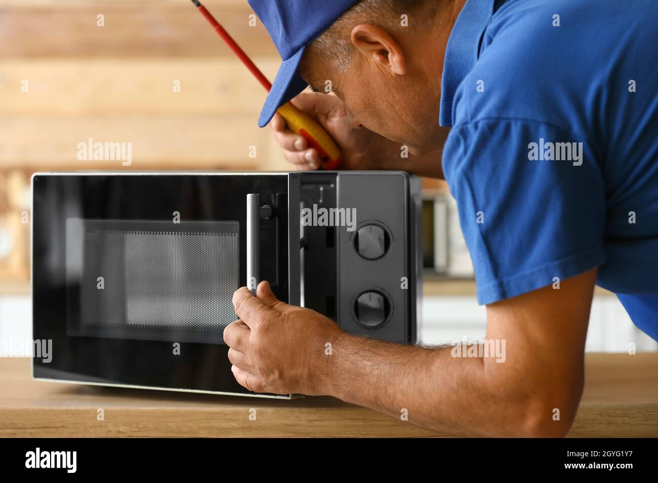 Male worker repairing microwave oven in kitchen Stock Photo