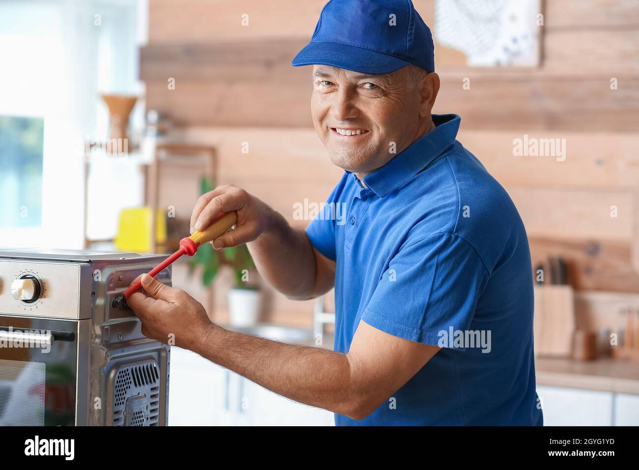 Male worker repairing microwave oven in kitchen Stock Photo