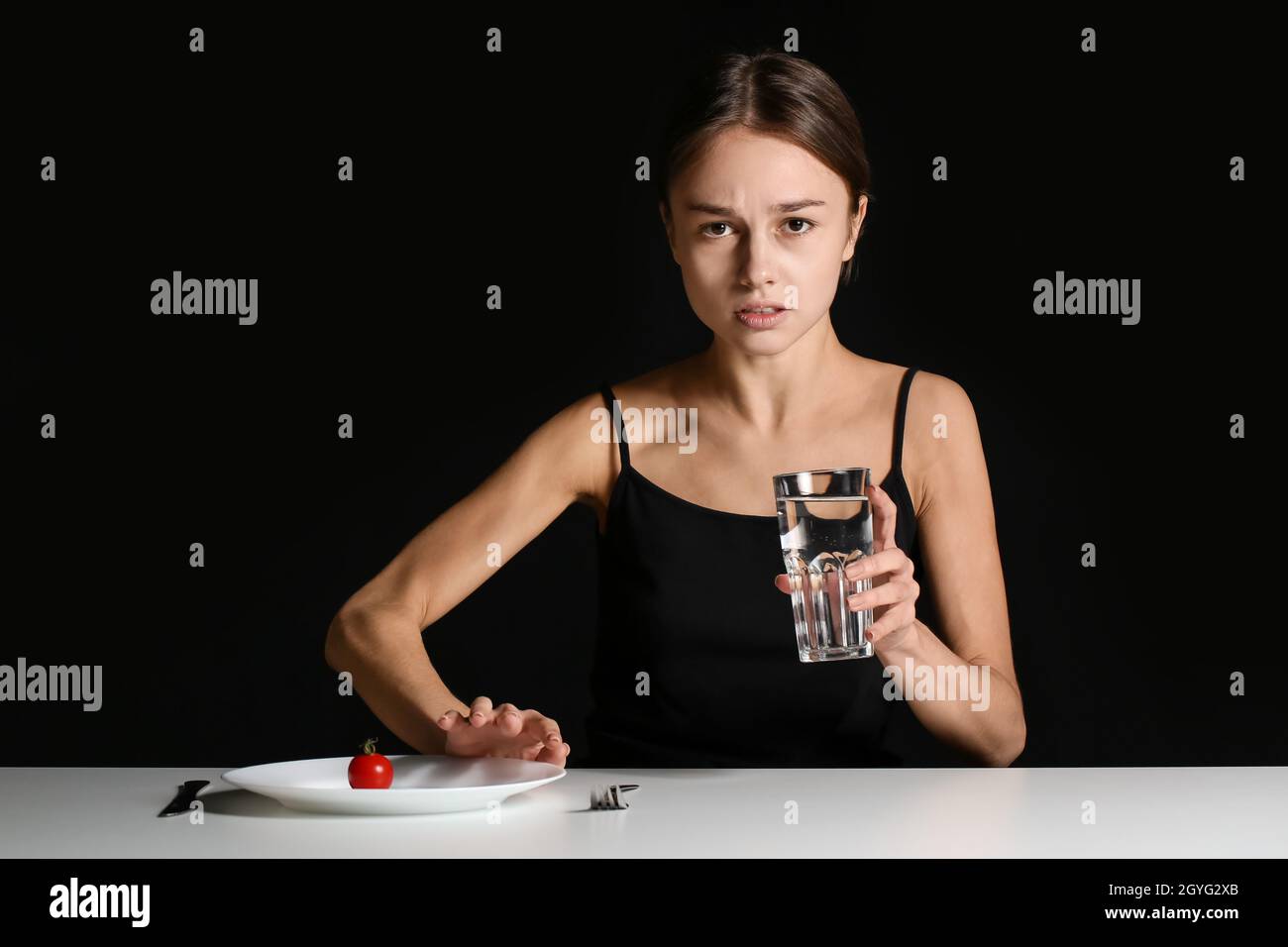 Young woman refusing from food at table on dark background. Anorexia ...