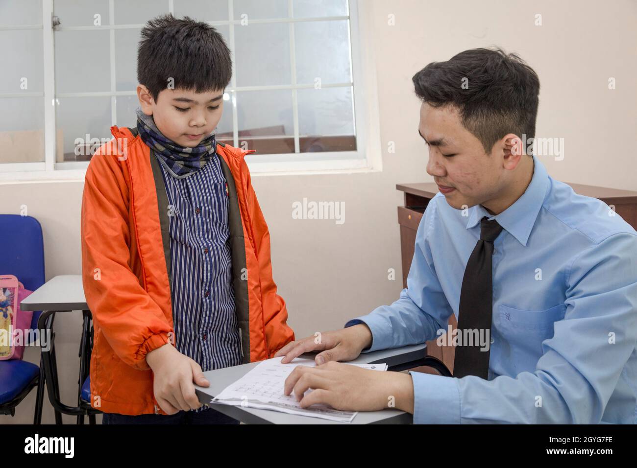 Male teacher and student work on problems in English Class. Stock Photo