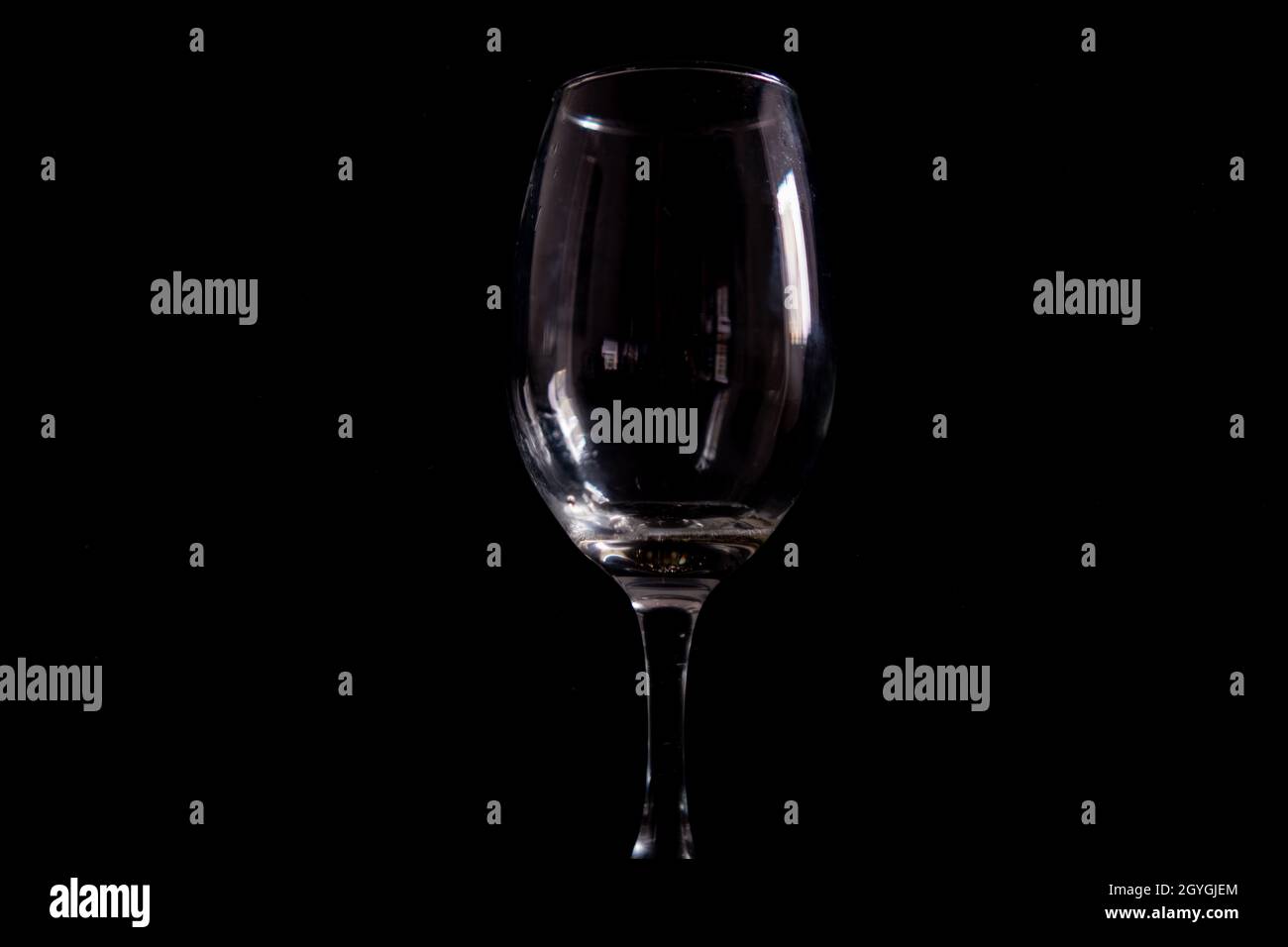 Light reflecting on empty glass goblet with black background Stock Photo