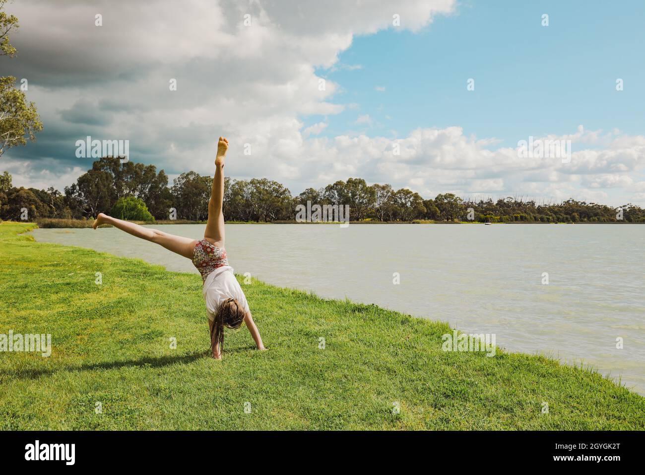 Girl doing handstand next to Lake in Boort, Victoria Australia Stock Photo