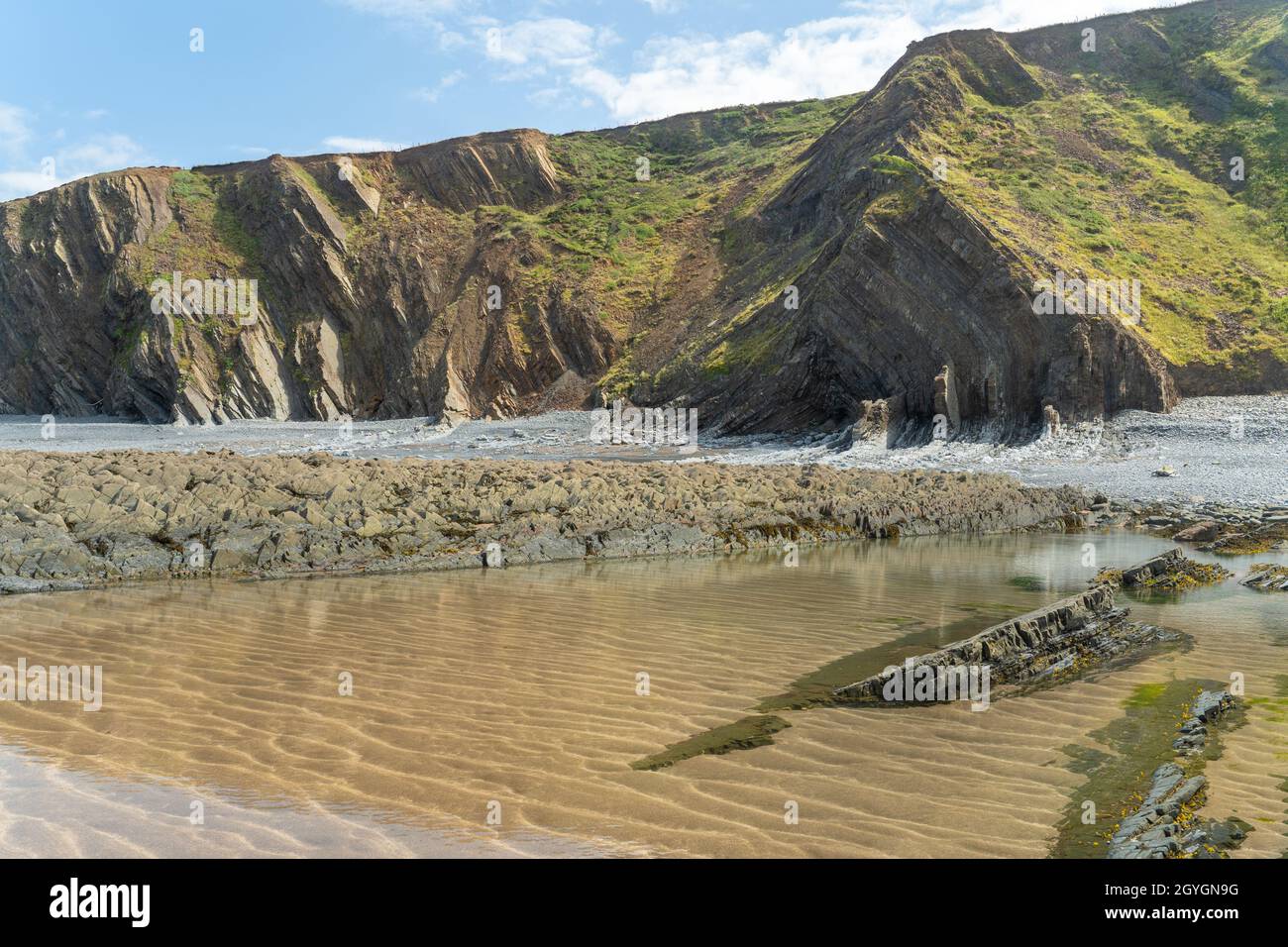 Speke's Mill Mouth near Hartland Quay on the north Devon coast at low tide looking up at the geologically interesting rocks and cliffs Stock Photo