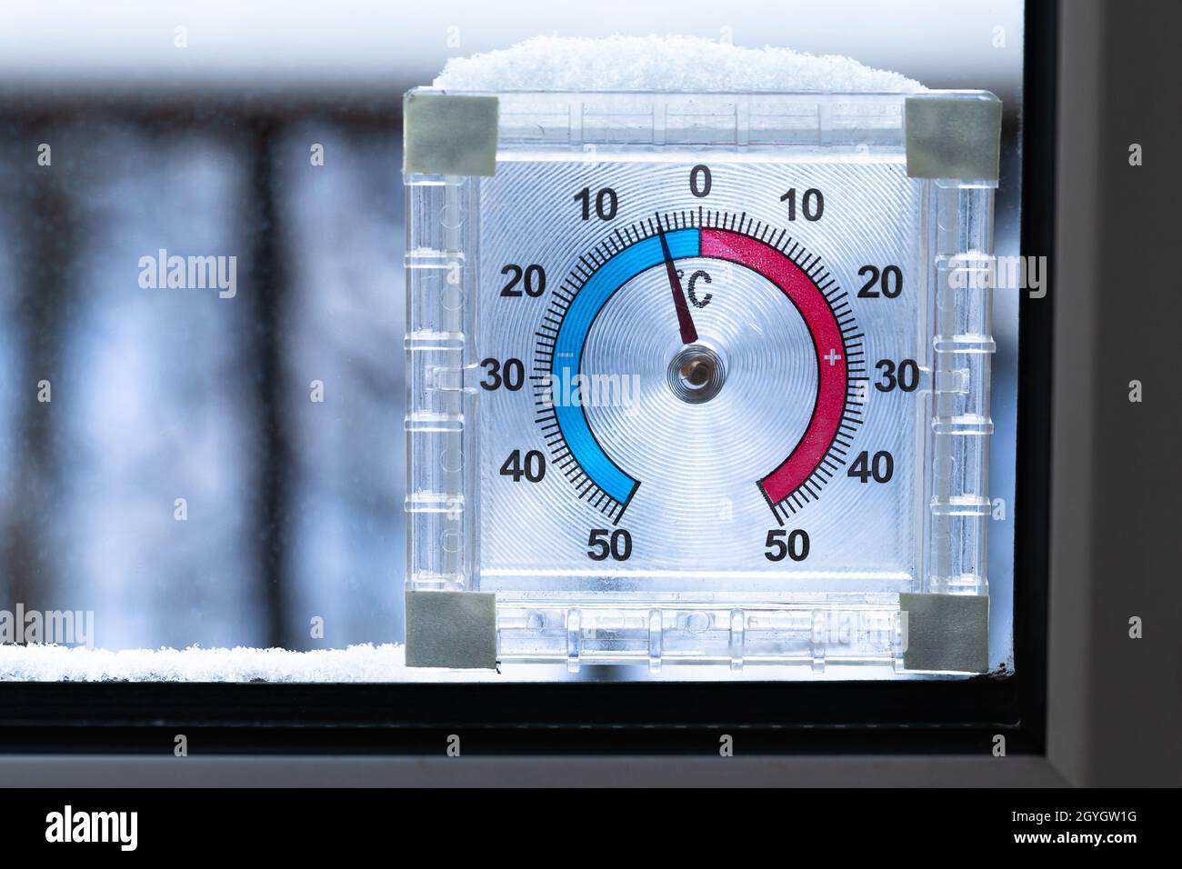 Outdoor window thermometer covering with snow shows negative temperature in degrees Celsius. Closeup photo with selective focus Stock Photo