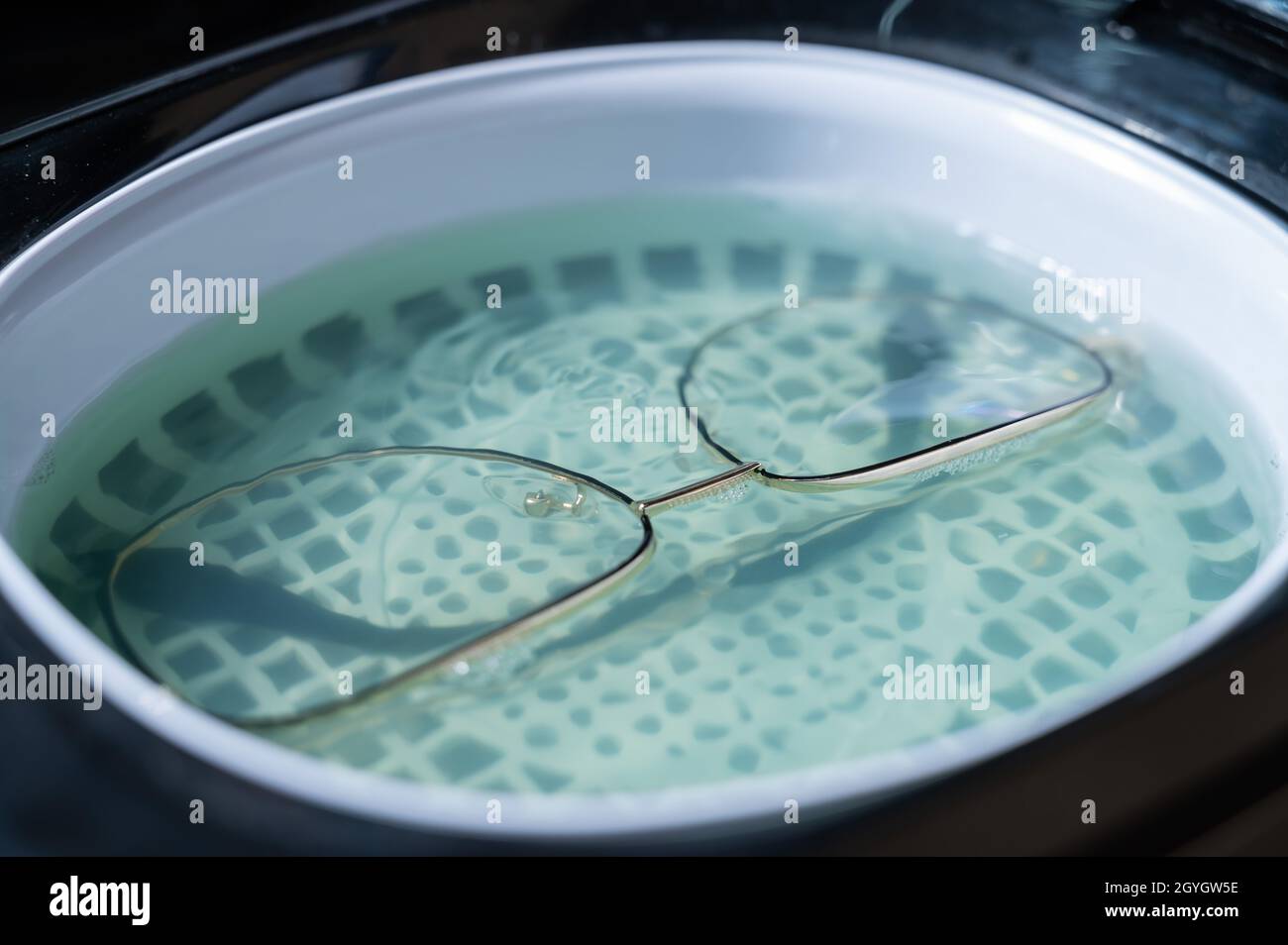 Ultrasound cleaning of glasses in solution. Optical technician repairs