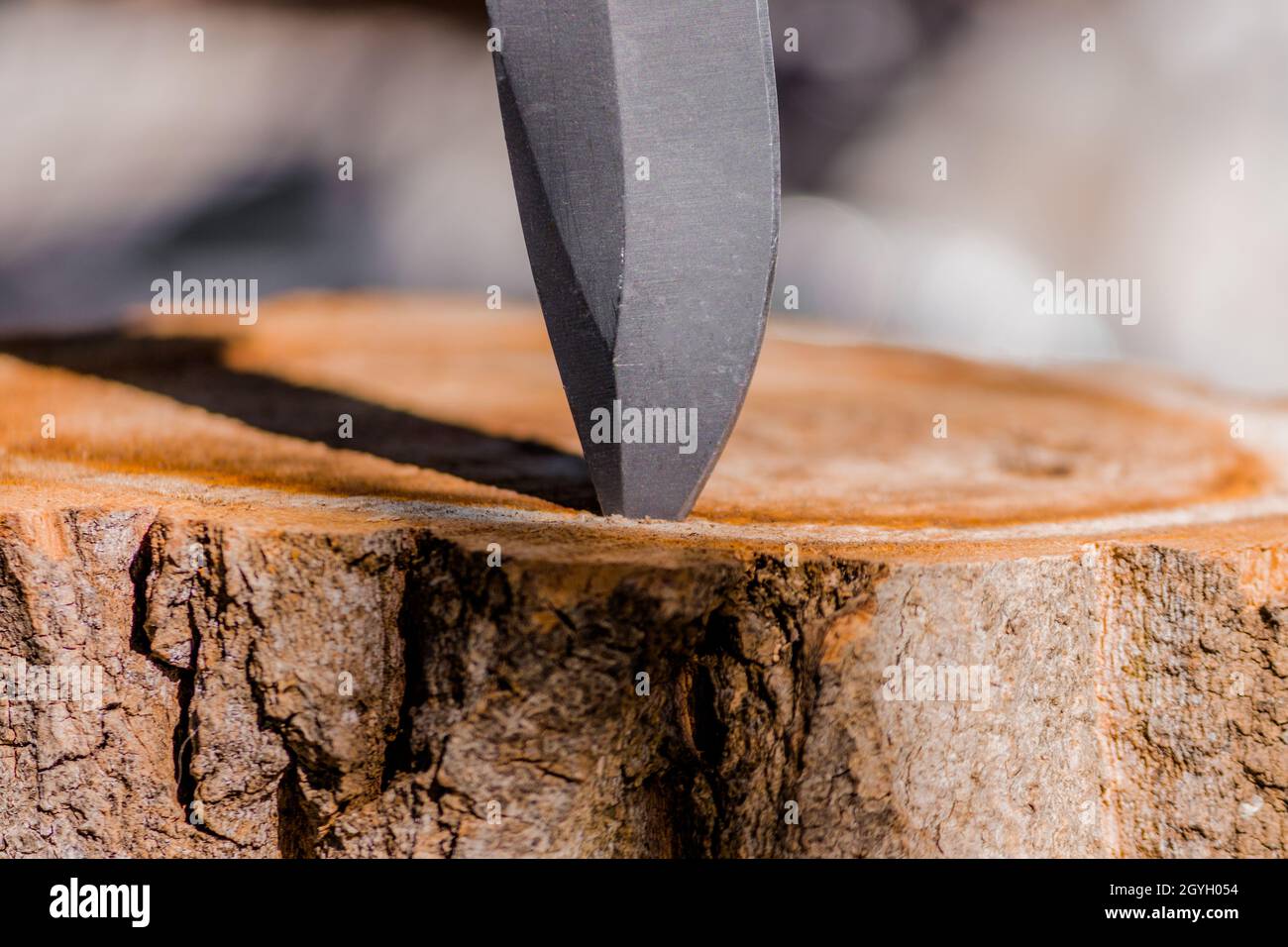 The sharp blade of a knife is stuck in a wooden stump and creates a shadow. Stock Photo