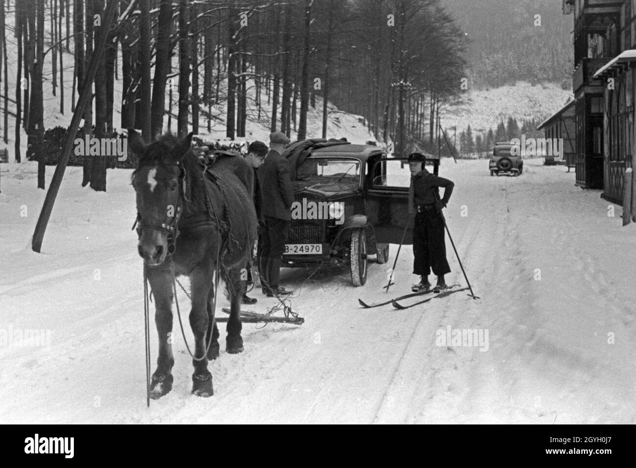 Ein Pferd hilft, ein liegengebliebenes Auto auf verschneiter Straße wieder  ans Fahren zu bekommen, Deutschland 1930er Jahre. A horse helping a car to  drive again on a snowed in street, Germany 1930s