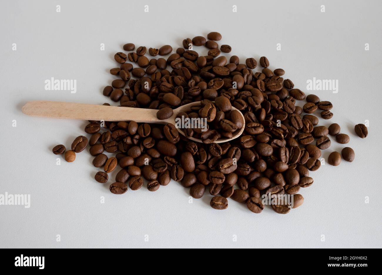Aromatic coffee beans in a wooden spoon, for the production of delicious coffee. Whole roasted coffee beans for grinding. Stock Photo