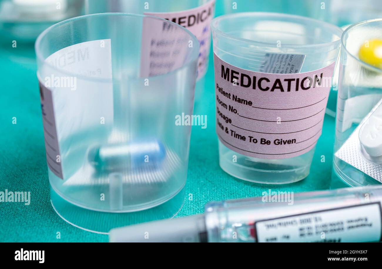 Diverse medication in glasses monodose along with insulin injectors in hospital, conceptual image Stock Photo