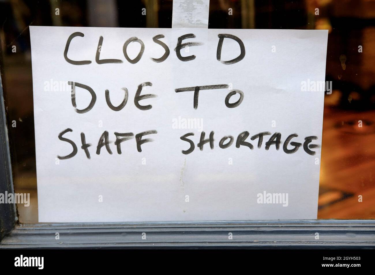 Closed due to staff shortage sign in window of high street shop. United Kingdom. Stock Photo
