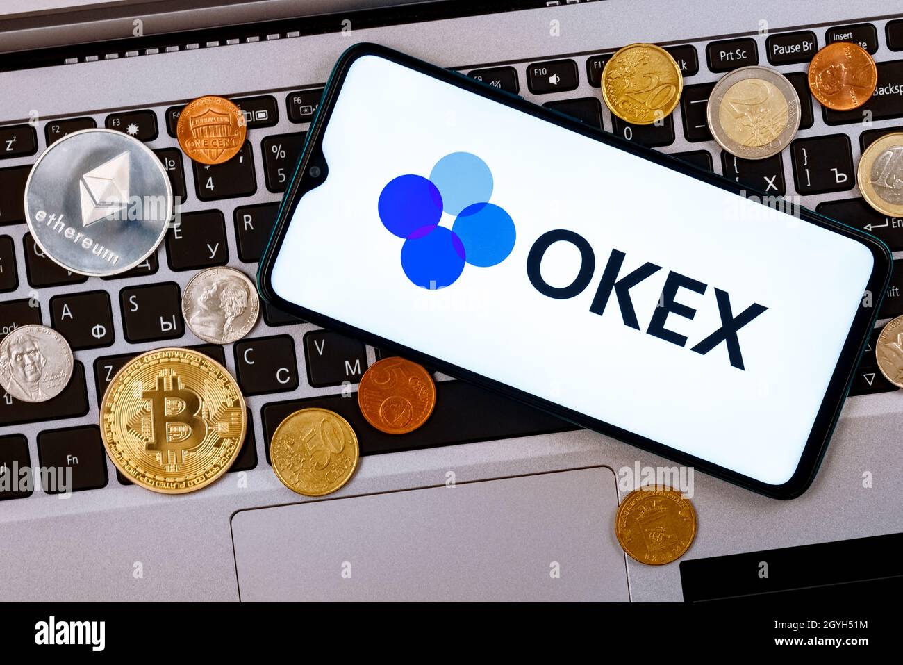 OKEx is a cryptocurrency exchange. A smartphone with the OKEx logo metal  coins, bitcoin, ethereum on a laptop keyboard Stock Photo - Alamy