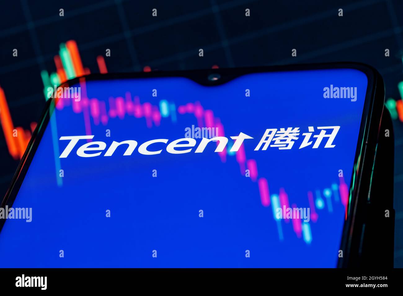 A smartphone with the Tencent logo on the background of the stock chart. Stock Photo