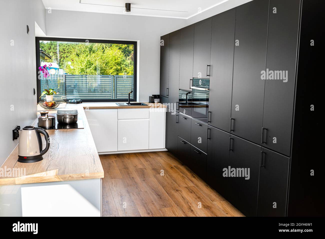 https://c8.alamy.com/comp/2GYH6W1/a-modern-kitchen-with-white-and-black-fronts-and-a-large-corner-window-vinyl-panels-on-the-floor-2GYH6W1.jpg