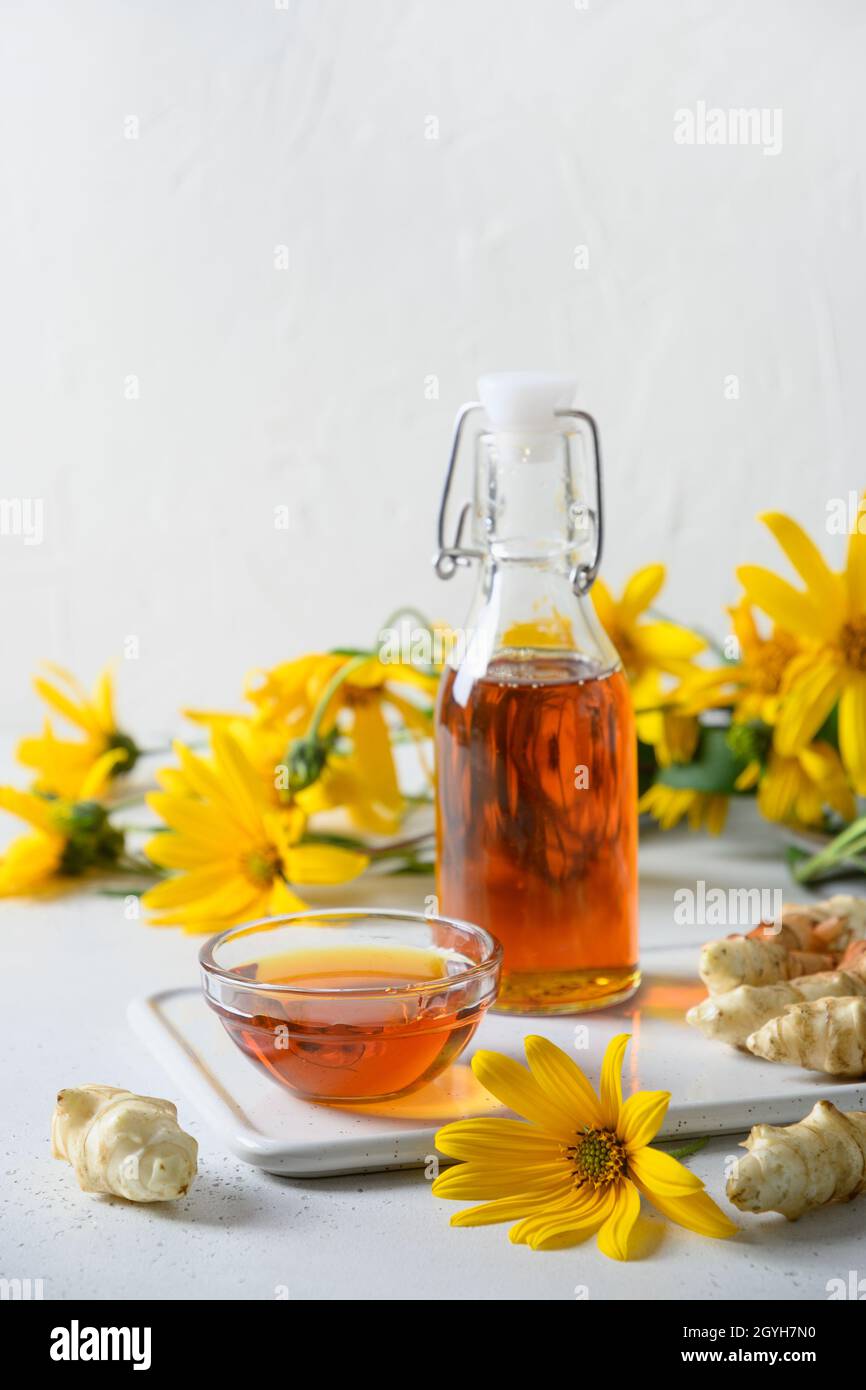 Jerusalem artichoke topinambour syrup in bowl and bottle on white