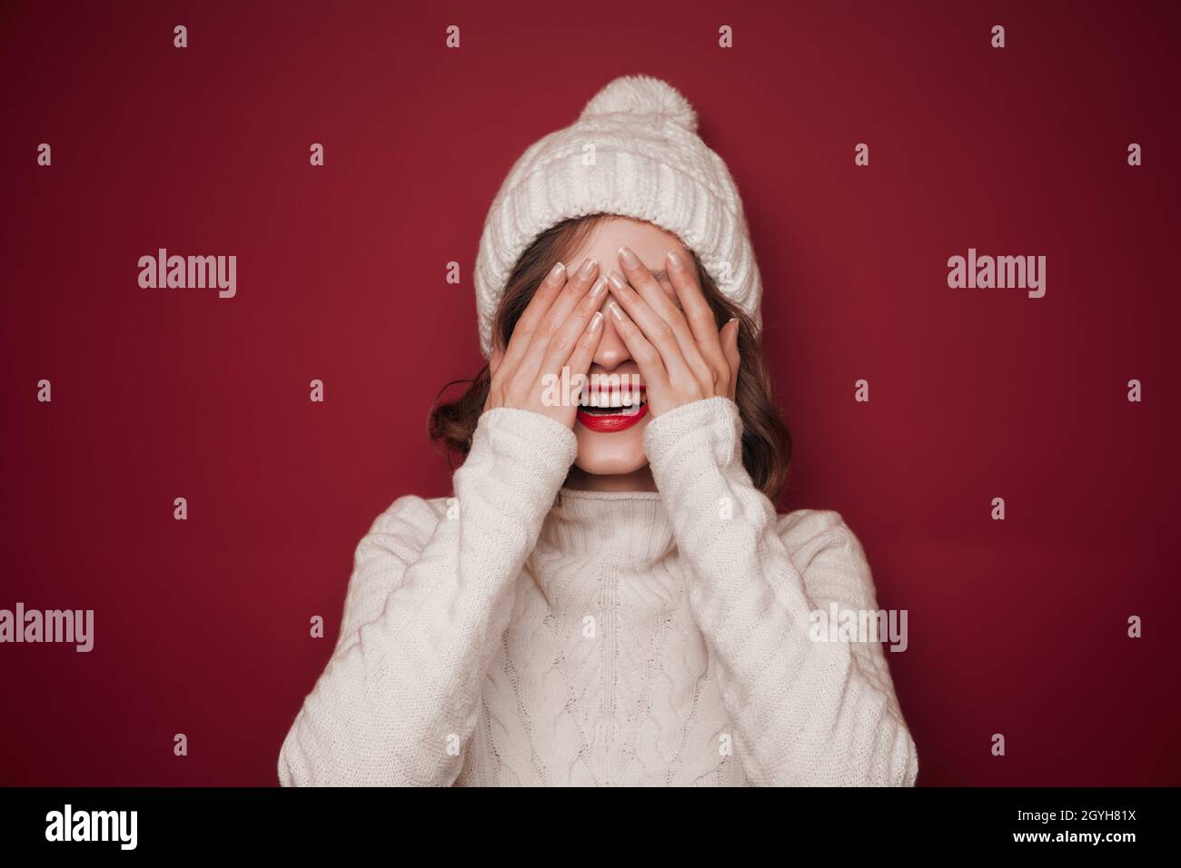 Cheerful smiling woman in sweater cover her eyes Stock Photo