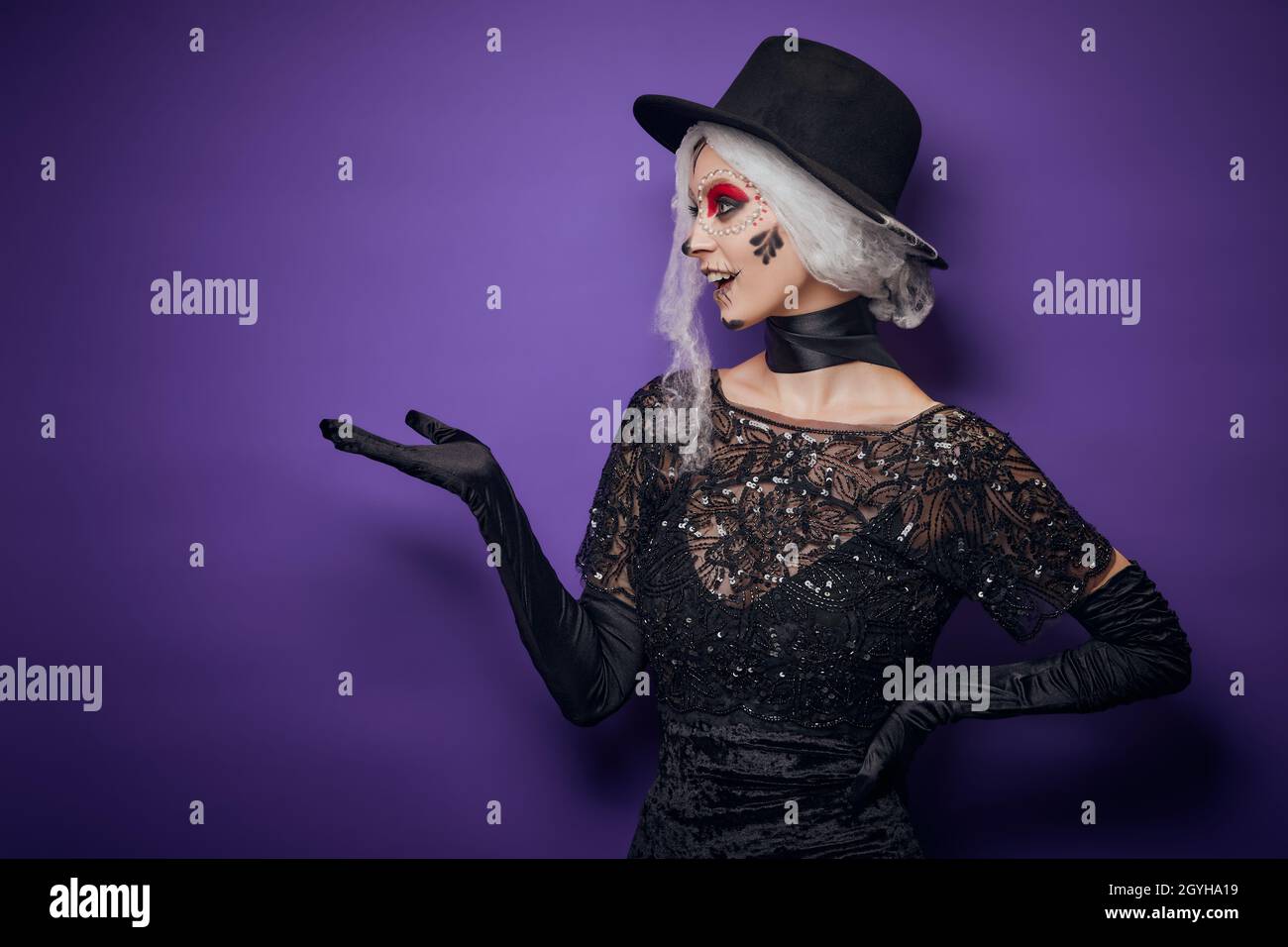 Cheerful young woman with grey hair in Halloween costume pointing Stock Photo