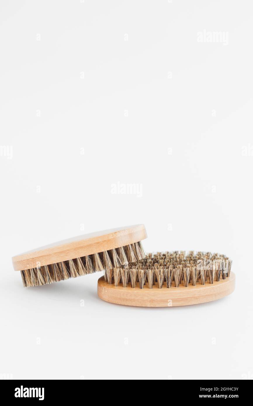 Two bristly brushes hug and lie together. Bad temper couple concept. Close up view of a bamboo beard brush with natural bristles on a white background Stock Photo