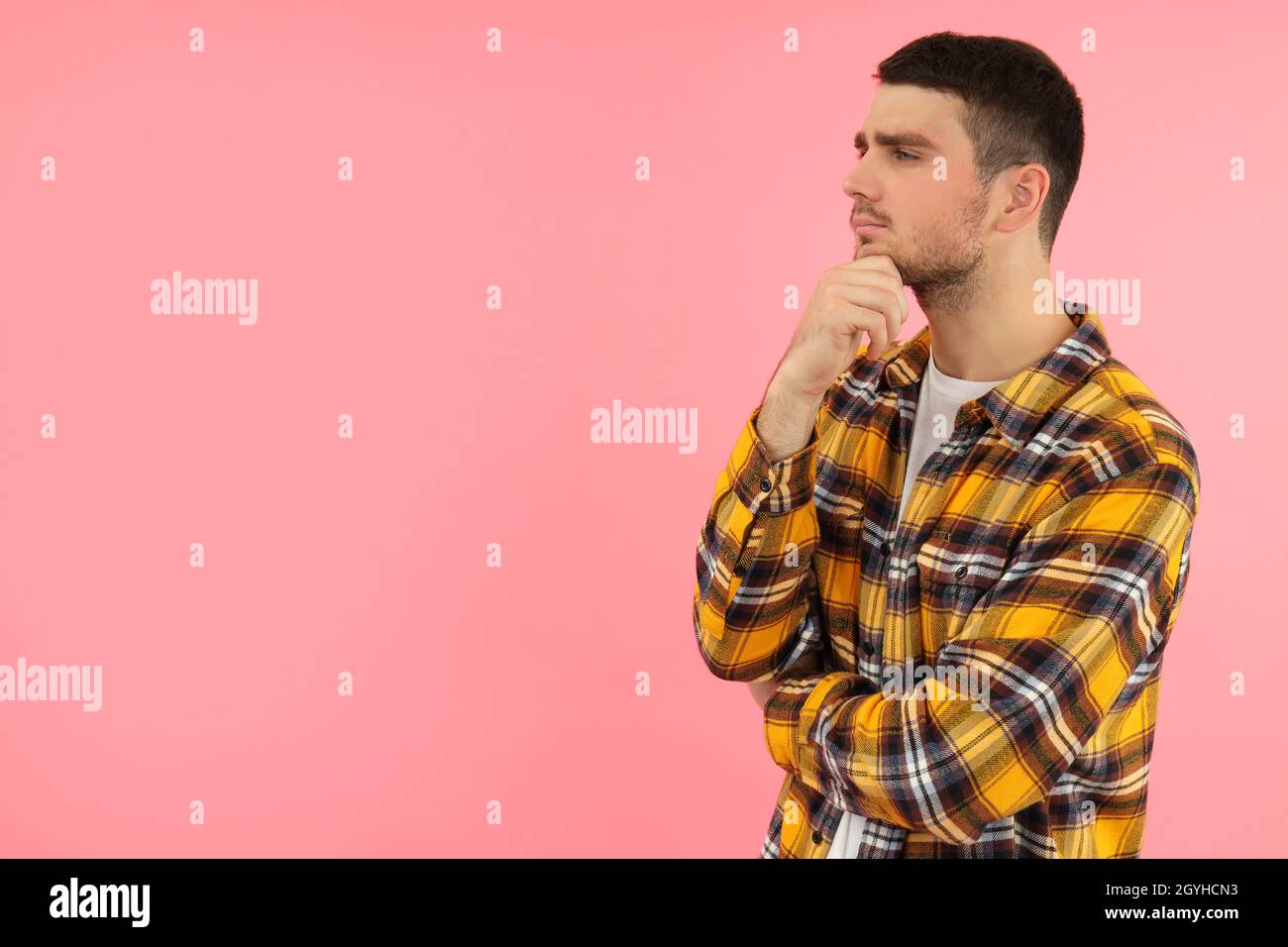 Pensive young man on pink background, space for text. Stock Photo