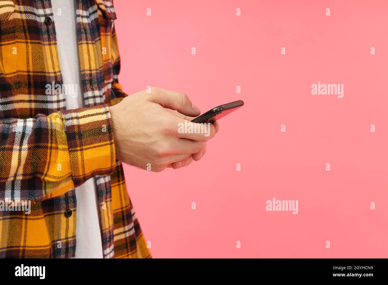 Man using phone on pink background, space for text. Stock Photo