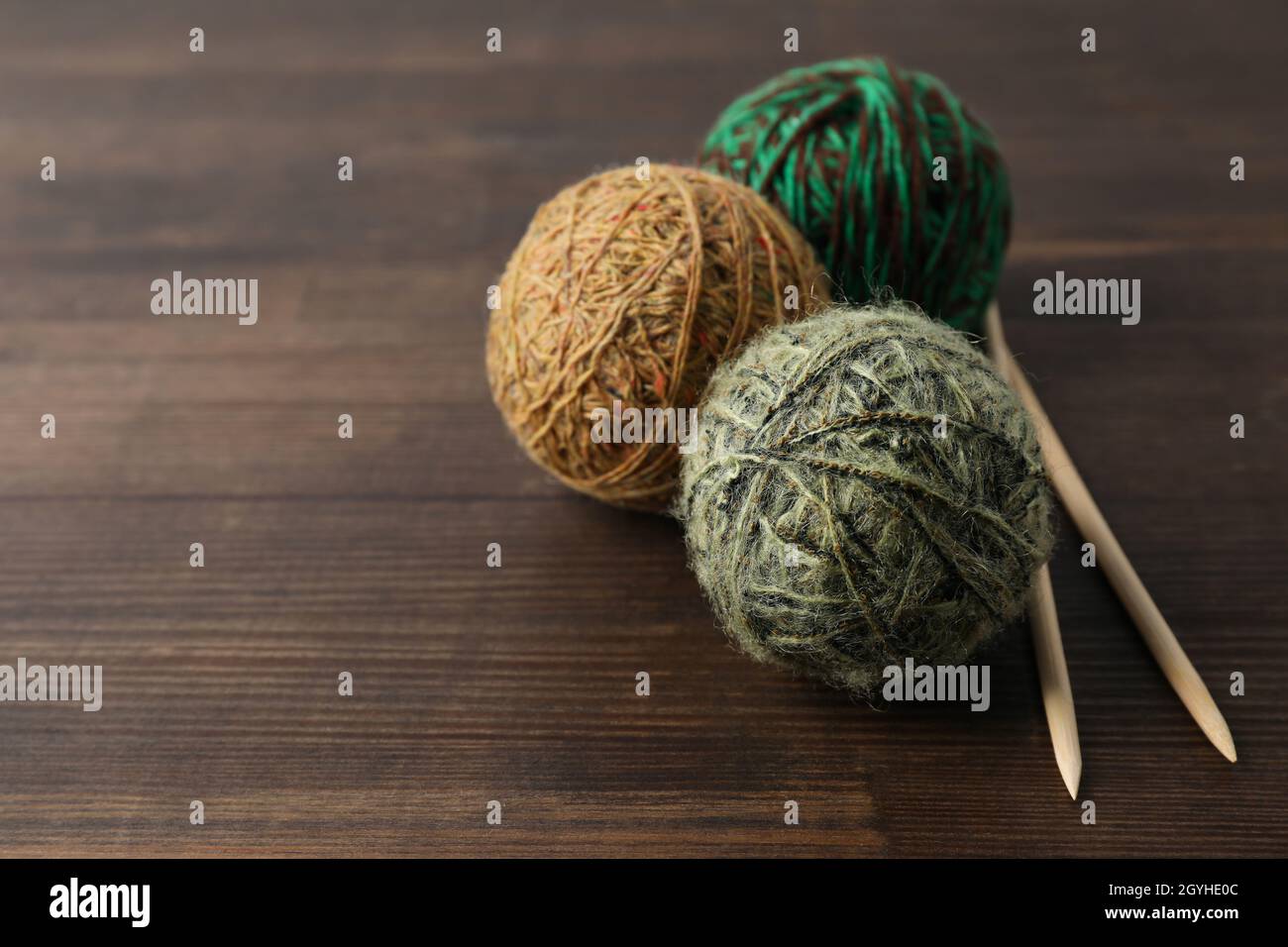 Multi colored balls of yarn with knitting needles on a wooden ...