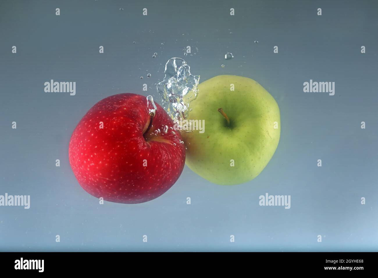 Two apples fall into water on a light background. Stock Photo