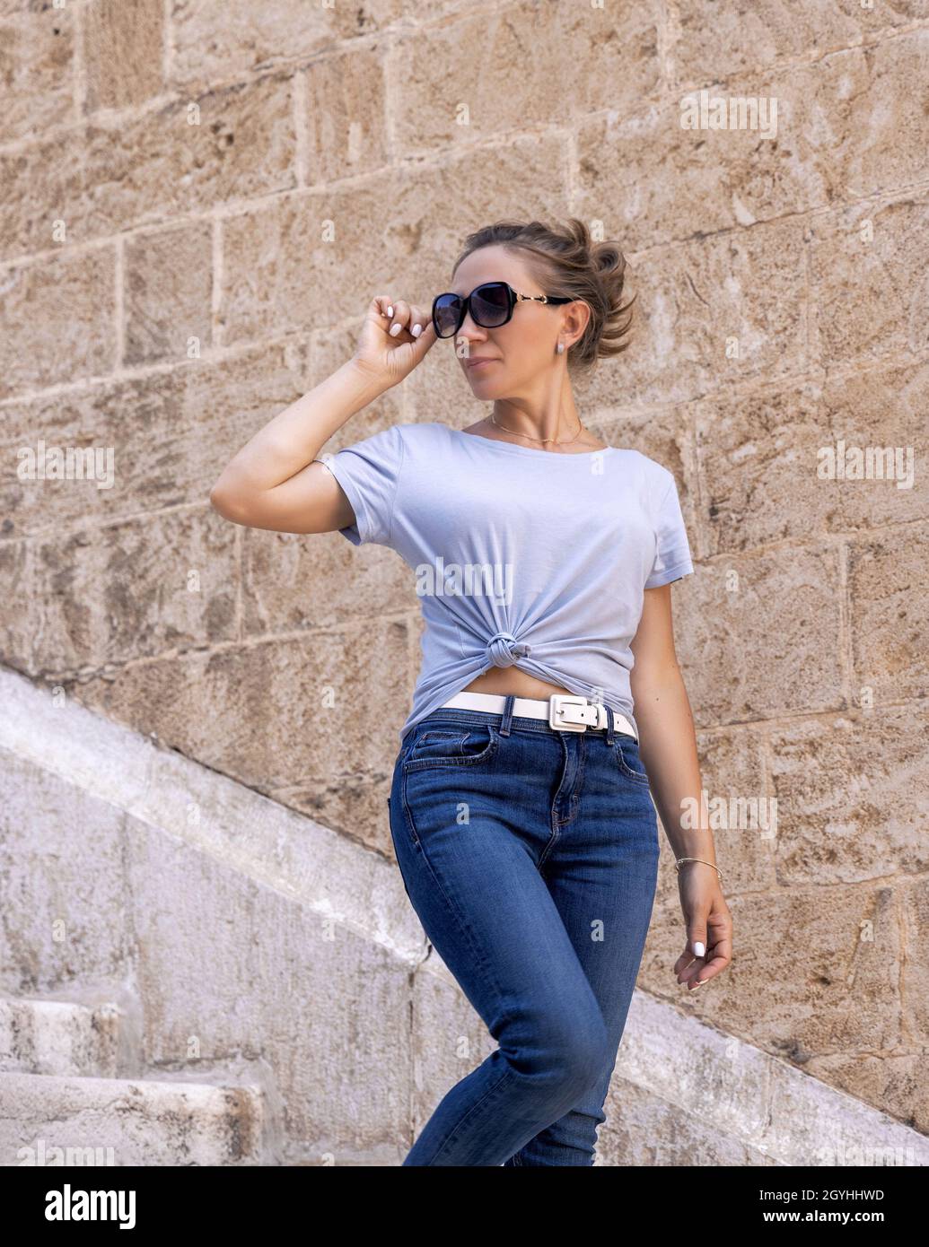 Women wearing t-shirt, jeans and sunglases going down the stairs and  looking back outdoor in a sunny summer day Stock Photo - Alamy