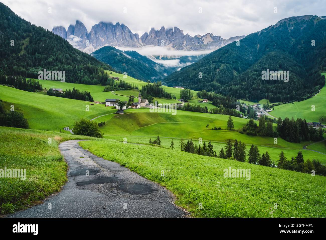 Hiking trail to St Magdalena church in Val di Funes valley, Dolomites, Italy. Furchetta and Sass Rigais mountain peaks in background Stock Photo