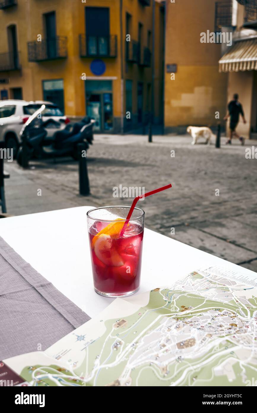 Travel map and a glass of lemonade on street cafe table against old city street Stock Photo