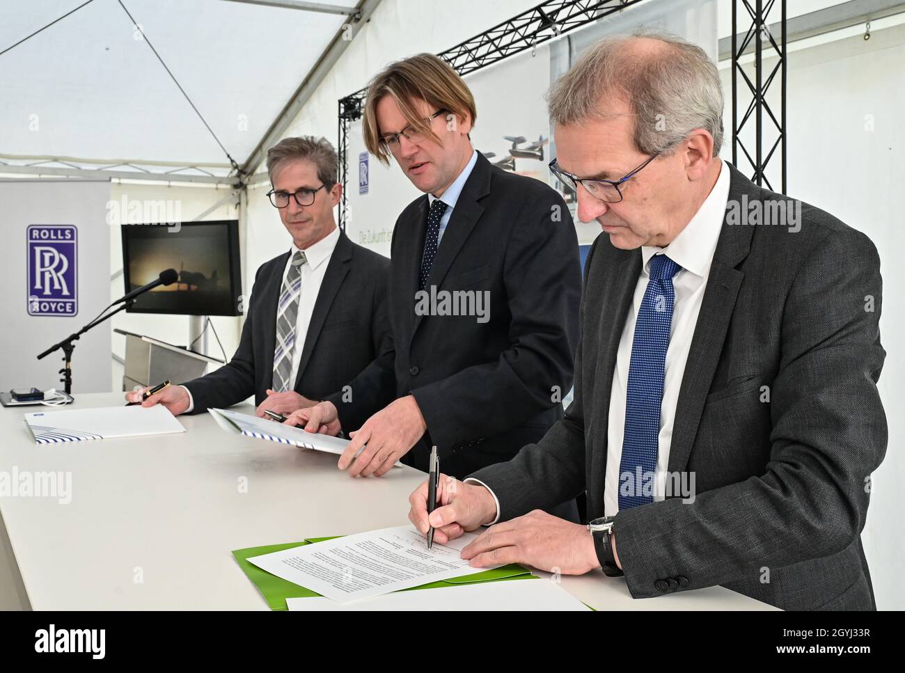 Cottbus, Germany. 08th Oct, 2021. Jörg Au (l), Managing Director Rolls-Royce Germany, Rob Watson (m), Head of Rolls-Royce Electrical and Hendrik Fischer, State Secretary at the Brandenburg Ministry of Economics, signing a Memorandum of Understanding to expand research and development capacity for hybrid-electric propulsion systems in Brandenburg. Rolls-Royce intends to drive forward the research and development of hybrid-electric propulsion systems for the next generation of aviation in Brandenburg. Credit: Patrick Pleul/dpa-Zentralbild/dpa/Alamy Live News Stock Photo
