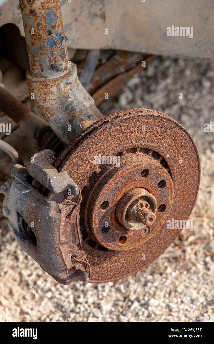 a rusty brake disc and calliper on an old rusty corroded car with the