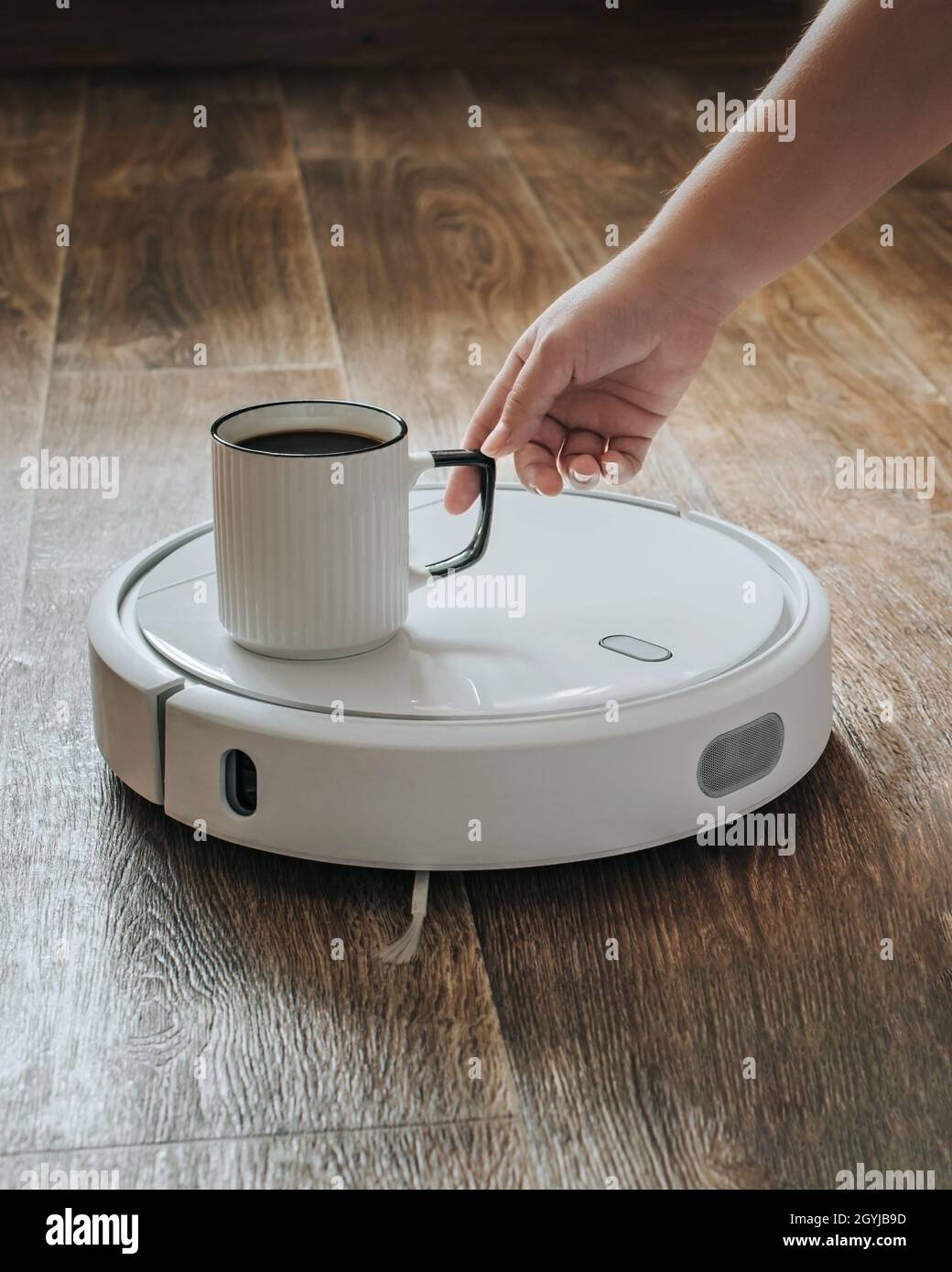 A robot vacuum cleaner brought a cup of coffee. Stock Photo