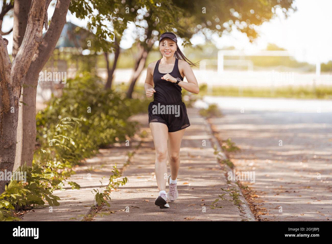 Young woman jogging outdoors in the city park on a beautiful summer day ...