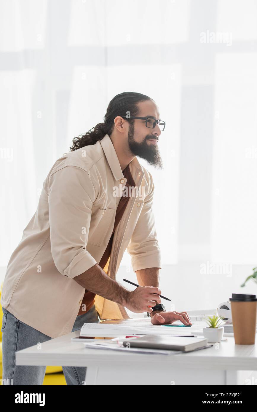 thoughtful hispanic architect looking away while working at home Stock Photo