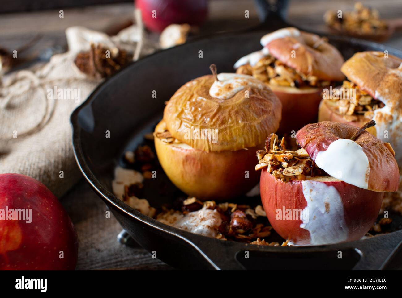 Homemade breakfast cereal with with fresh baked apples and granola topped with cinnamon and yogurt. Served on rustic and wooden table. Stock Photo