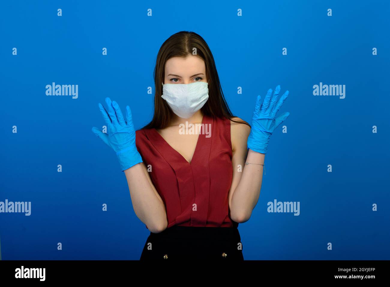 Female in a protective medical mask and blue gloves on blue background ...