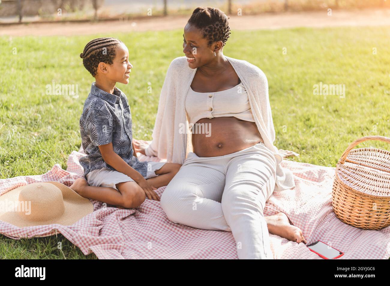 Happy playful Afro mother and son having fun in park doing a picnic together - Family love concept Stock Photo