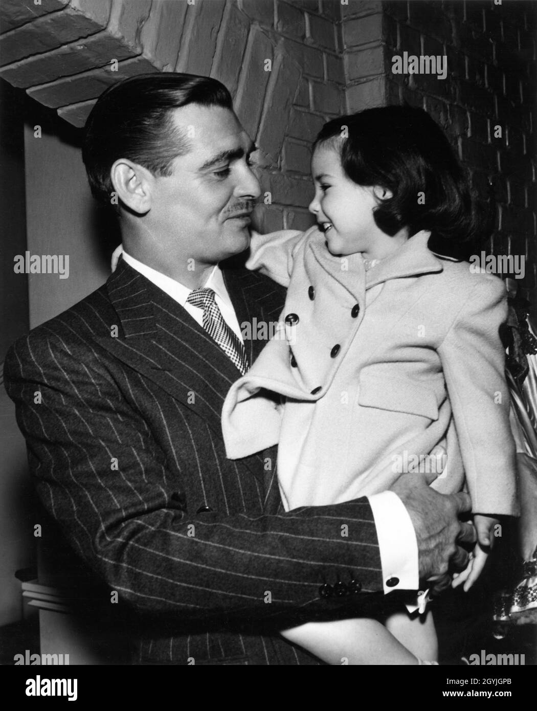 CLARK GABLE on set candid with 3 year old child actress DIANE PERRINE (playing Deborah Kerr's daughter in the film) during filming of THE HUCKSTERS 1947 director JACK CONWAY novel Frederick Wakeman costume supervisor Irene producer Arthur Hornblow Jr. Metro Goldwyn Mayer Stock Photo