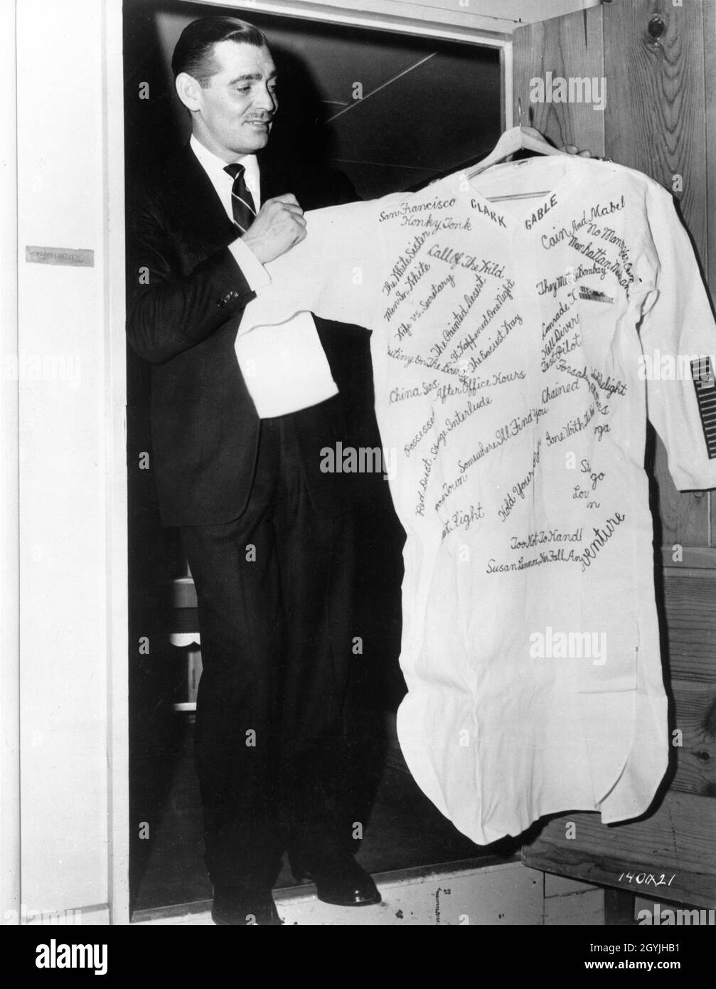 CLARK GABLE standing at the door of his Portable Dressing Room holding an embroidered night shirt listing all his films given as a 46th Birthday Gift during filming of THE HUCKSTERS 1947 director JACK CONWAY novel Frederick Wakeman costume supervisor Irene producer Arthur Hornblow Jr. Metro Goldwyn Mayer Stock Photo
