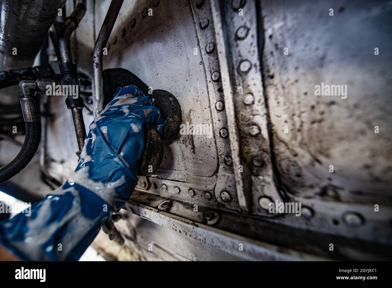 Guy Du, a contractor who works for Starlight Corporation cleans panels located near the landing gear a C-17 Globemaster III during an aircraft wash at March Air Reserve Base, California, Jan. 7, 2020. Aircraft are washed routinely to prevent corrosion and help promote aerodynamics. (U.S. Air Force photo by Joshua J. Seybert) Stock Photo