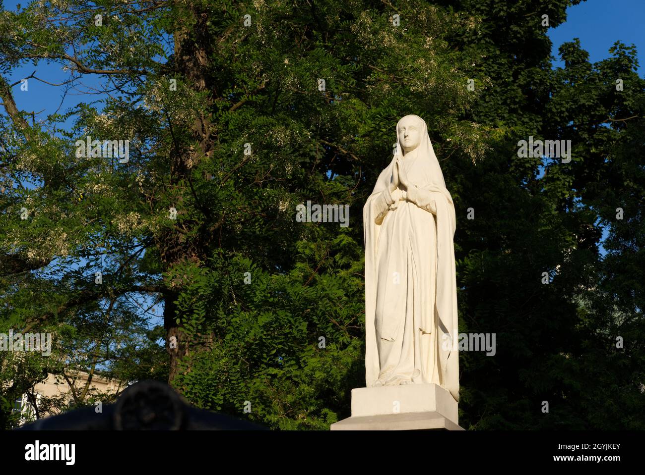 white stone statue of Virgin Mary on the church yard Stock Photo