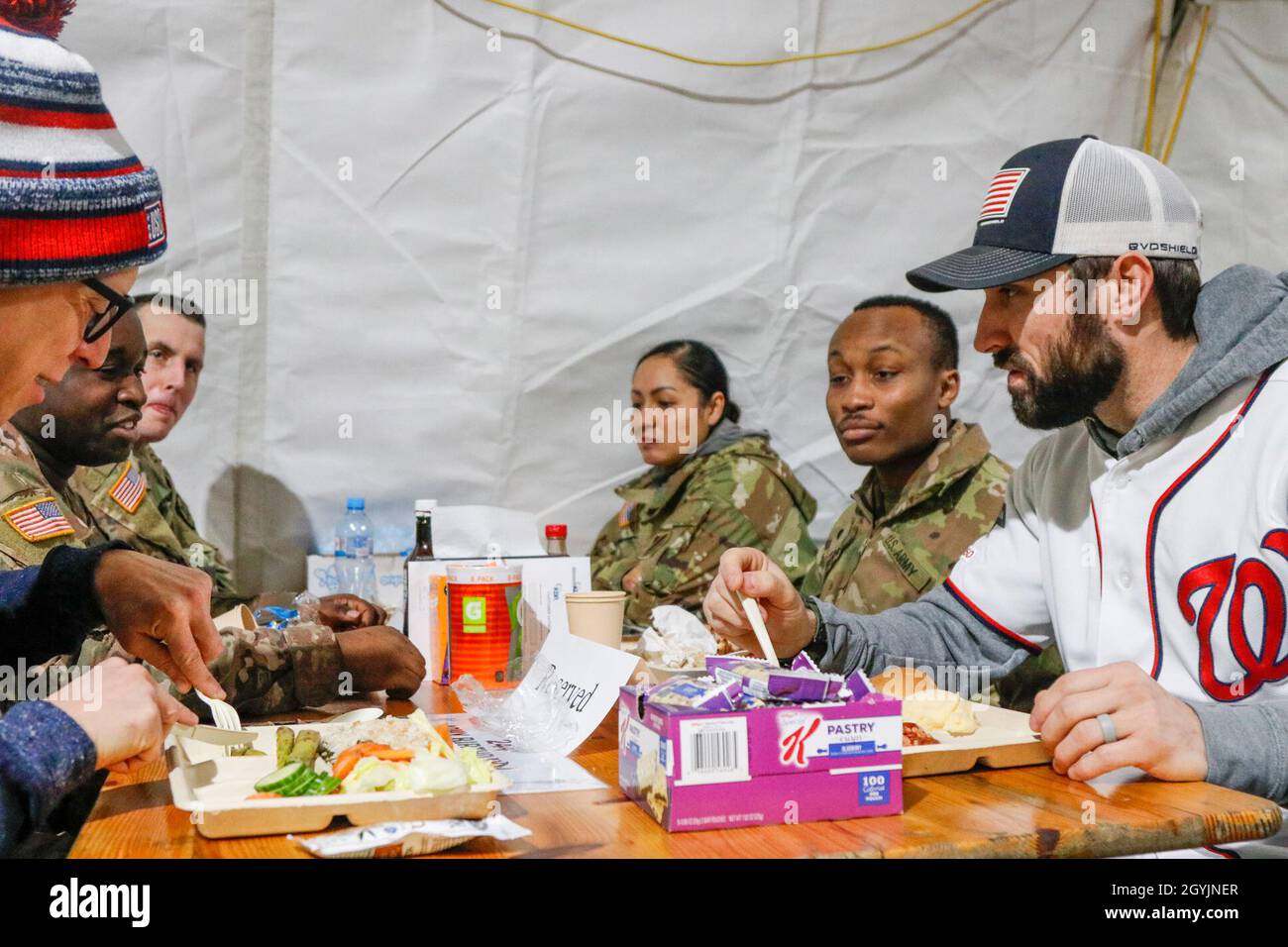 From left in the foreground, actor and television writer Brad Morris and  Washington Nationals outfielder Adam Eaton eat with Soldiers at the dining  facility before a United Service Organizations show on Powidz