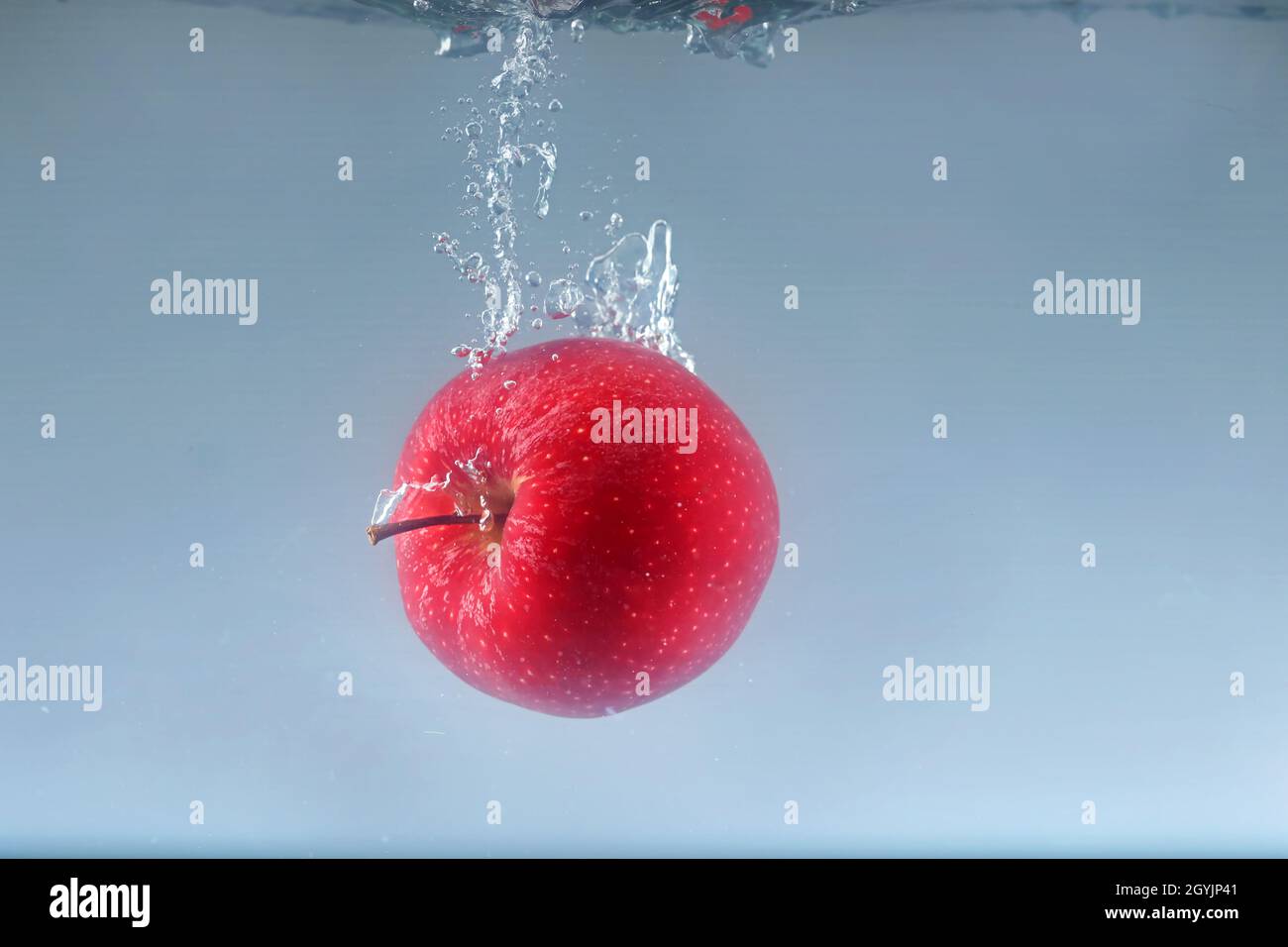 Apple falls into water on a light background. Stock Photo