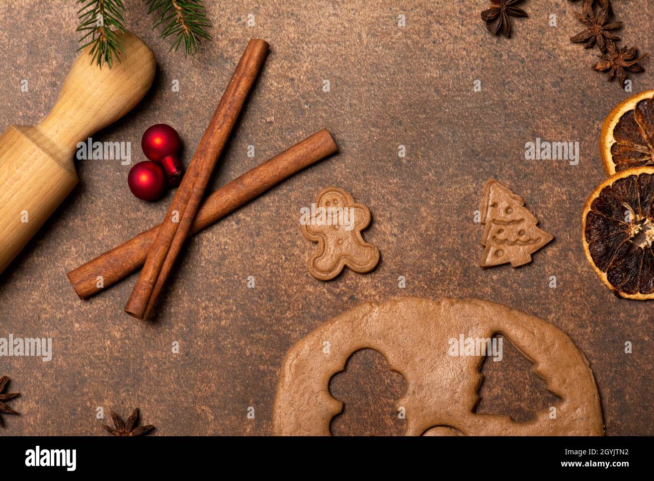 Gingerbread dough, a gingerbread man cookie, a Christmas tree cookie, a rolling pin, spices, red Christmas tree ornaments. Holidays are coming. Stock Photo